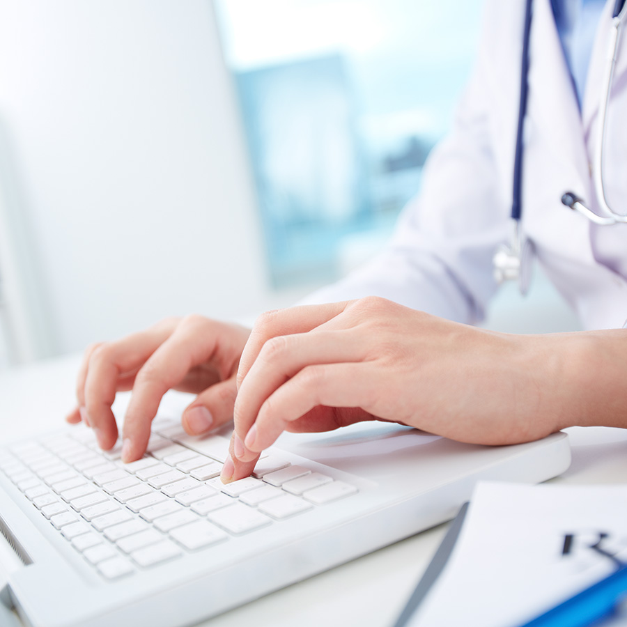 Close-up of hands of a nurse typing on laptop